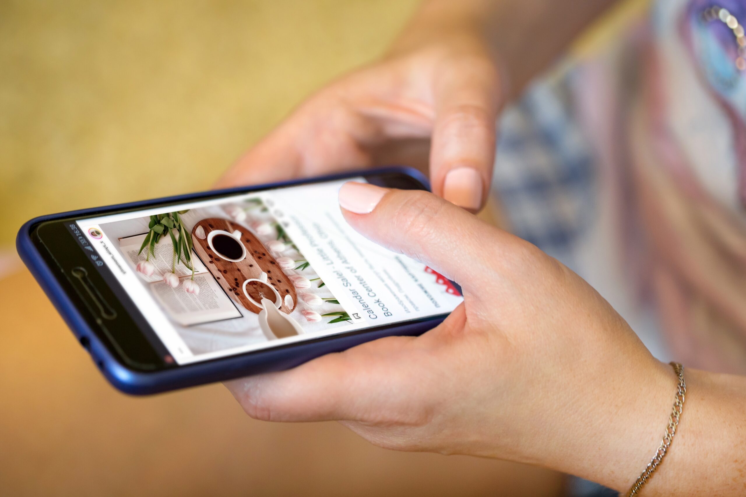 Eine Frau hält ein Handy in der Hand auf der eine Website geöffnet ist.