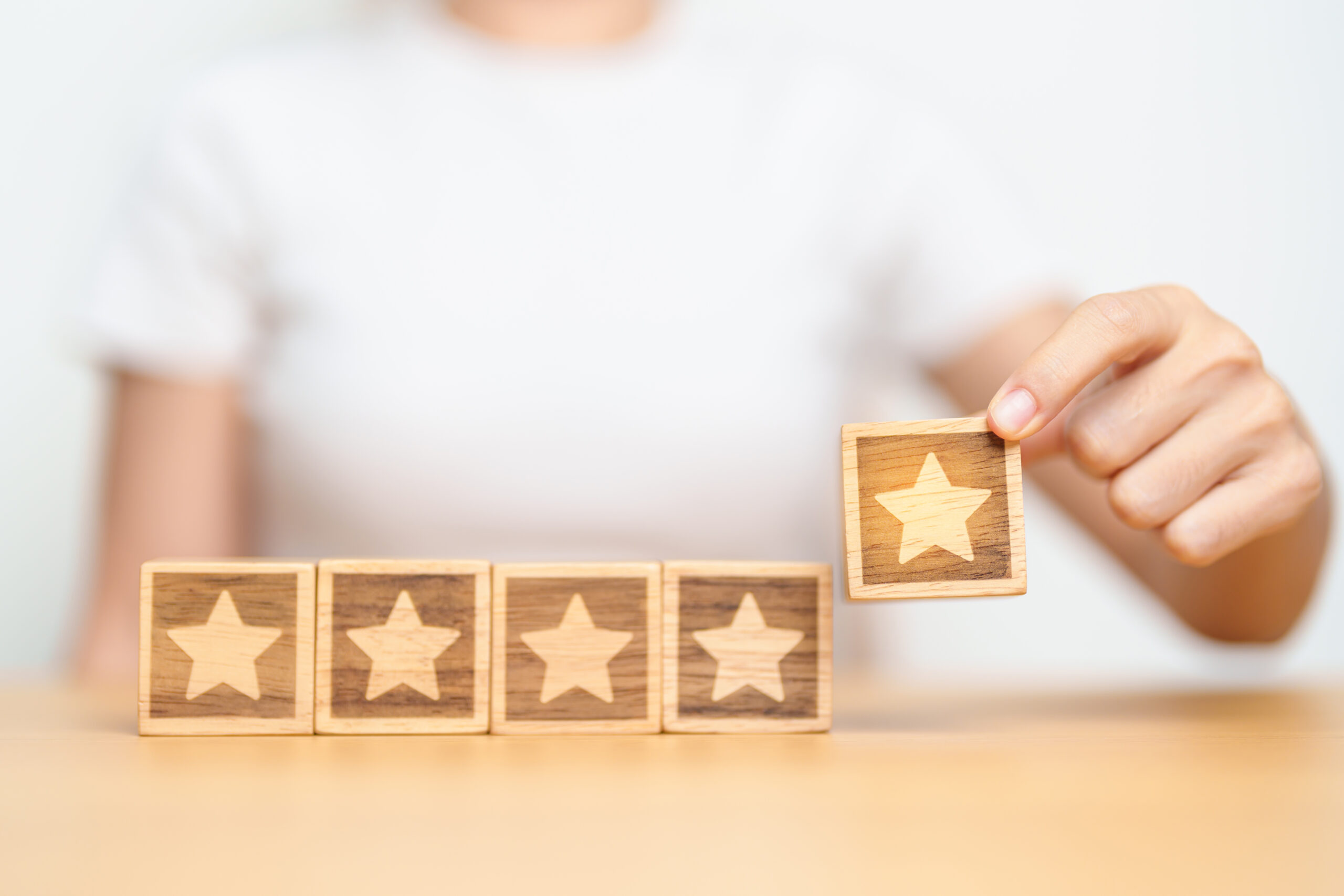 eine Hand hält einen Holzstern und stellt ihn zu vier anderen